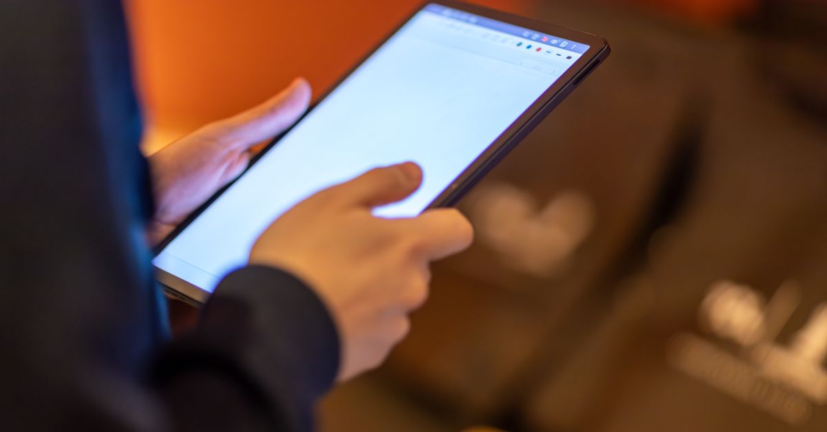 Persona leyendo un boletín digital en una tableta sobre una mesa de madera