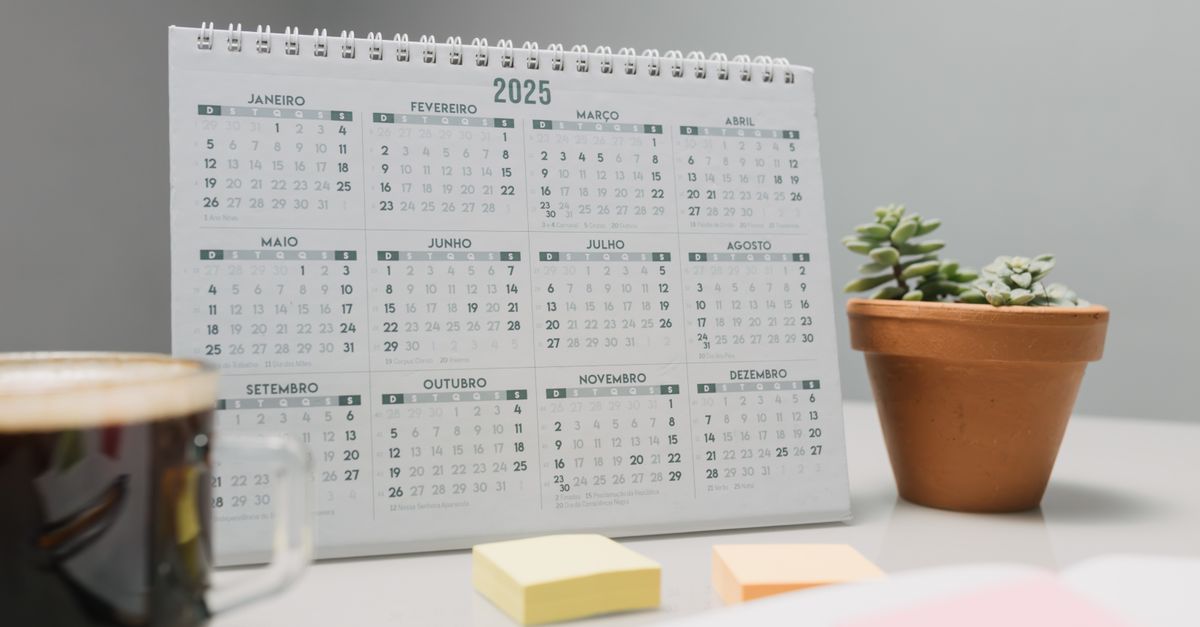Calendario de pared con notas y marcas junto a una libreta abierta